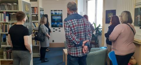 Návštěvníci vernisáže sledují komentář autorky k vystaveným fotografiím Návštěvníci vernisáže sledují autorku výstavy jak hovoří o svých fotografiích