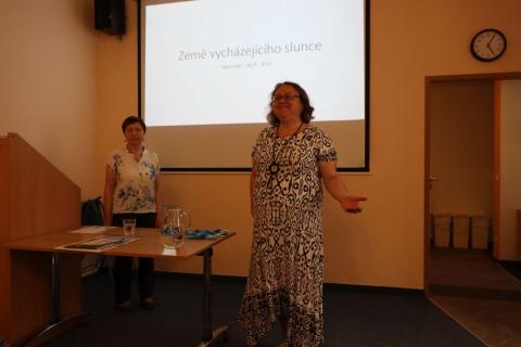 Zahájení besedy Přednášející Marcela Buřilová stojí před promítacím plátnem a sleduje proslov vedoucí knihovny, která vítá návštěvníky