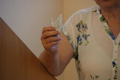 Origami jeřáb Detail na ruku přednášející, která drží papírového orgiami - jeřába.